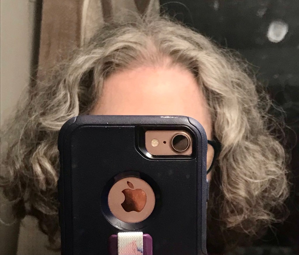 Bathroom mirror selfie. Reflection of me taking image in which phone obscures all but my shiny forehead and my gray and brown self-inflicted bob! 